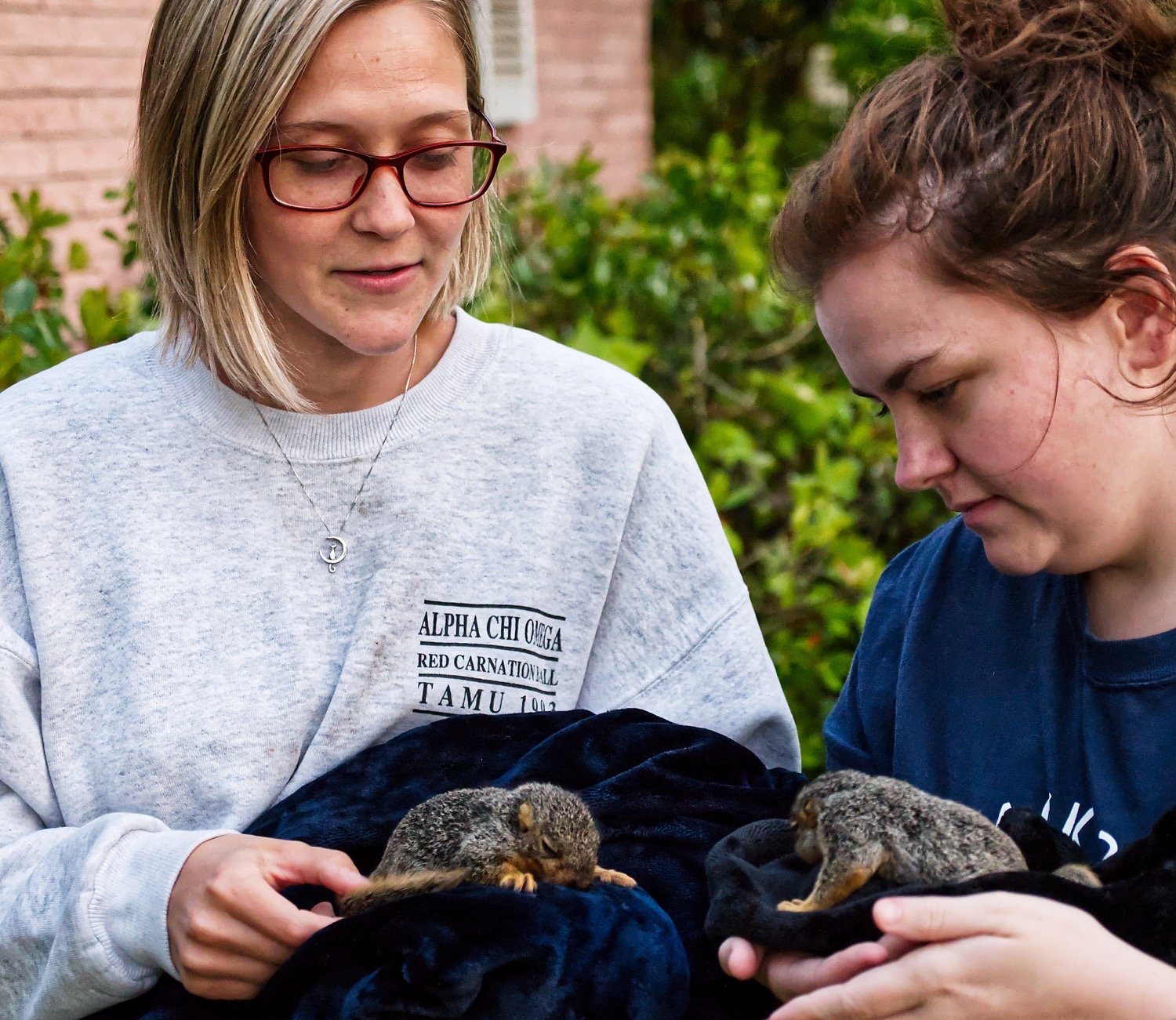 Tifani Pogue (left) and Brianna Gaylor hold a couple of baby squirrels whose home was knocked into Pogue’s residence by the winds Sunday.